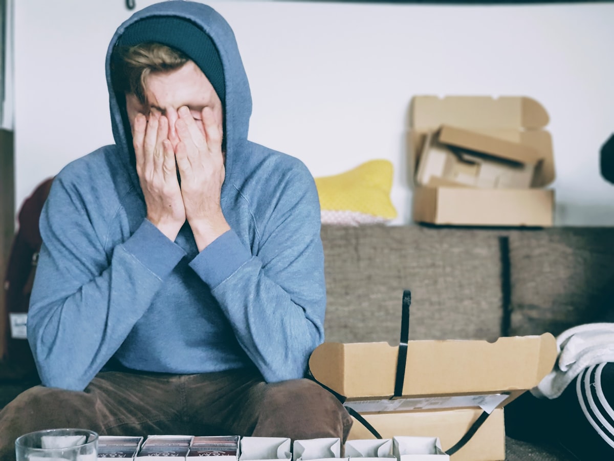 A developer in a hoodie with their face buried in their hands — the universal posture of cognitive overload