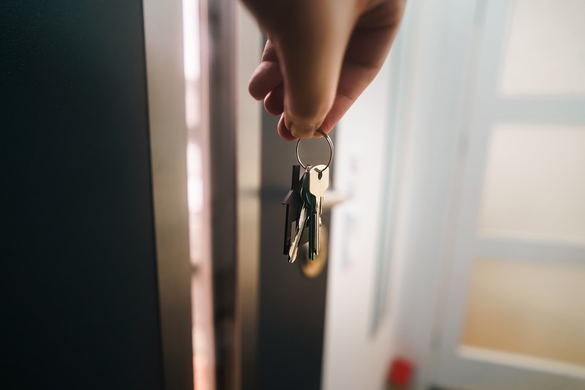 A hand holding a keyring near an open door — representing Apple opening its walled garden to Google's AI models for on-device intelligence