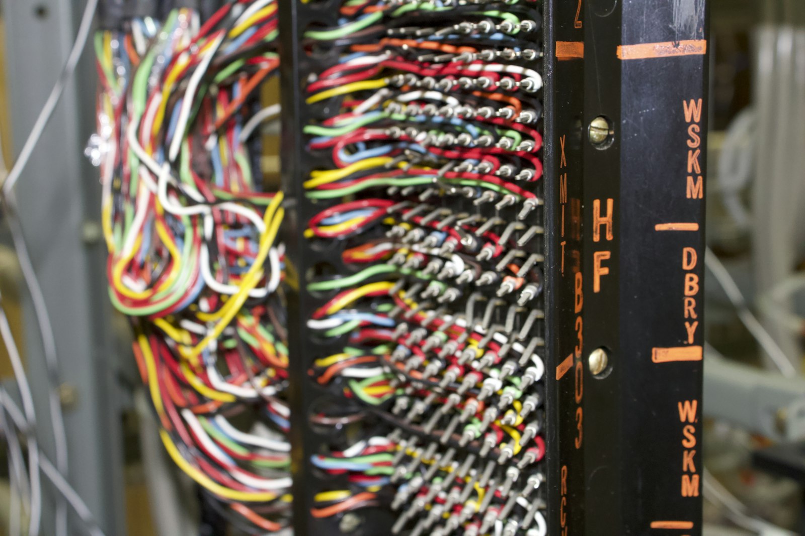 A tangled mass of colorful telephone wires on the left resolving into a neatly organized black patch panel on the right — the same shape as replacing scattered URLSession calls with one clean networking layer.