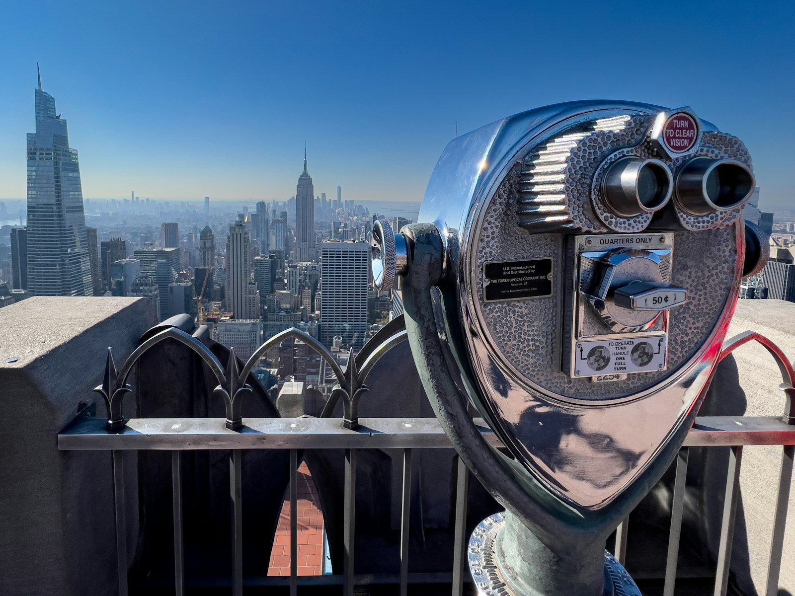 A coin-operated viewfinder overlooking the New York City skyline — representing the shift to pay-per-use AI coding tools where every token costs money