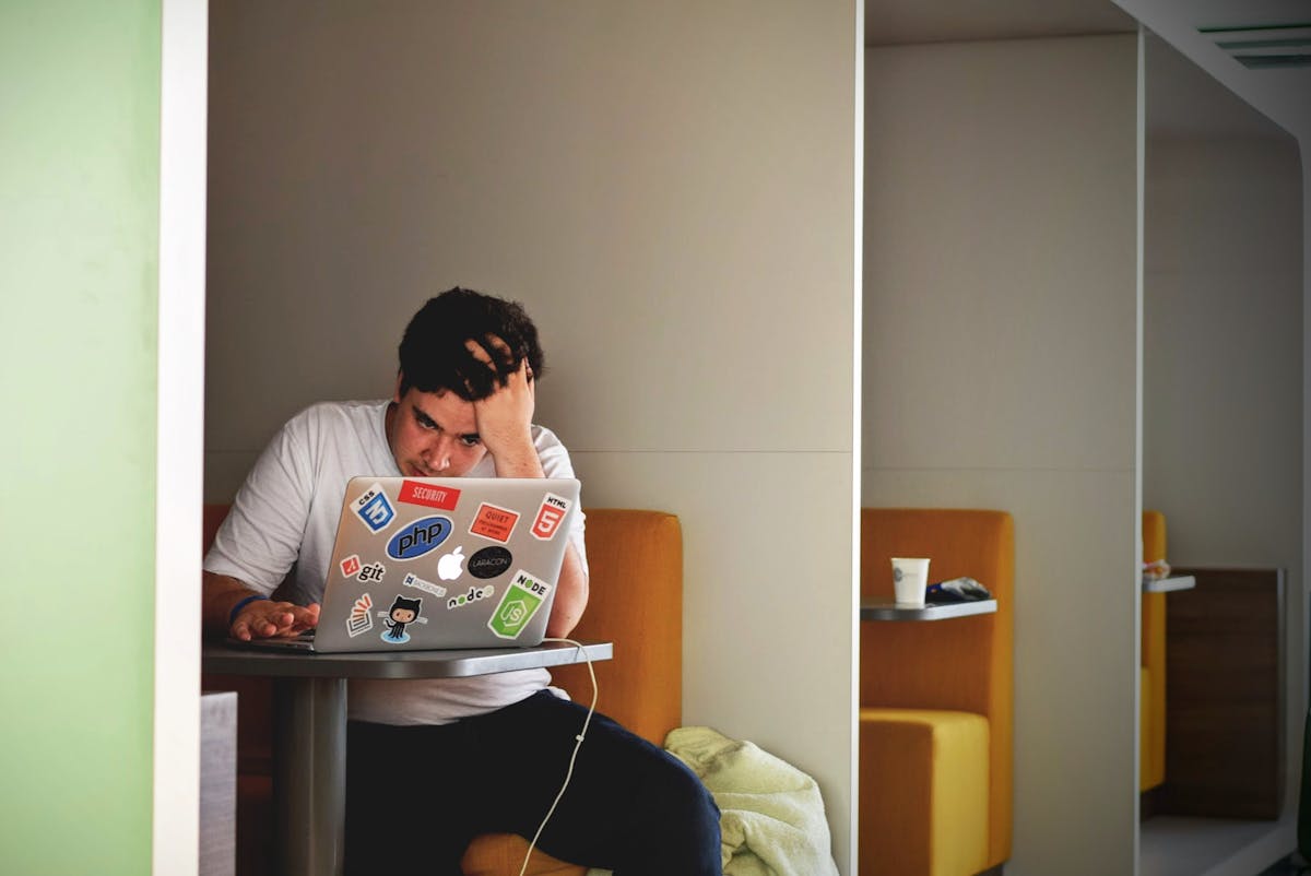A frustrated developer at a laptop — the face of a generation told to learn to code, now watching AI take the wheel