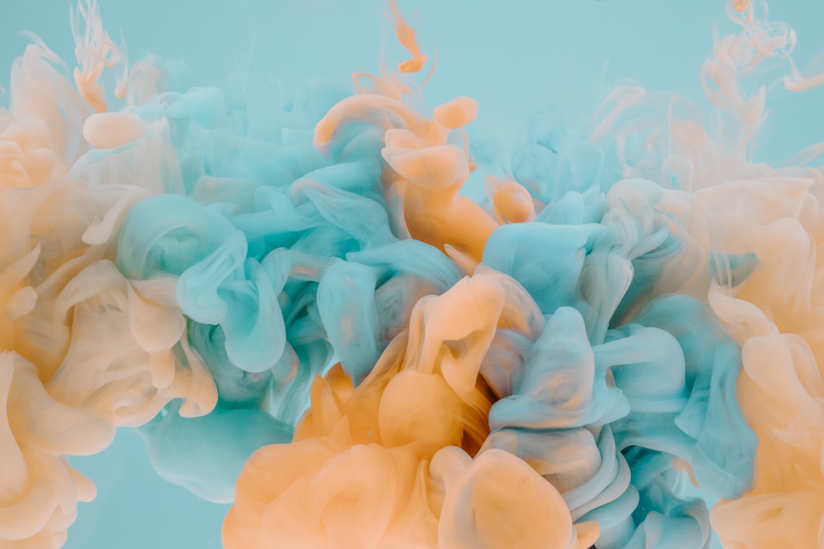 Orange and teal ink diffusing through water, translucent layers blending and morphing into each other — the visual metaphor for layering and morphing Liquid Glass effects.