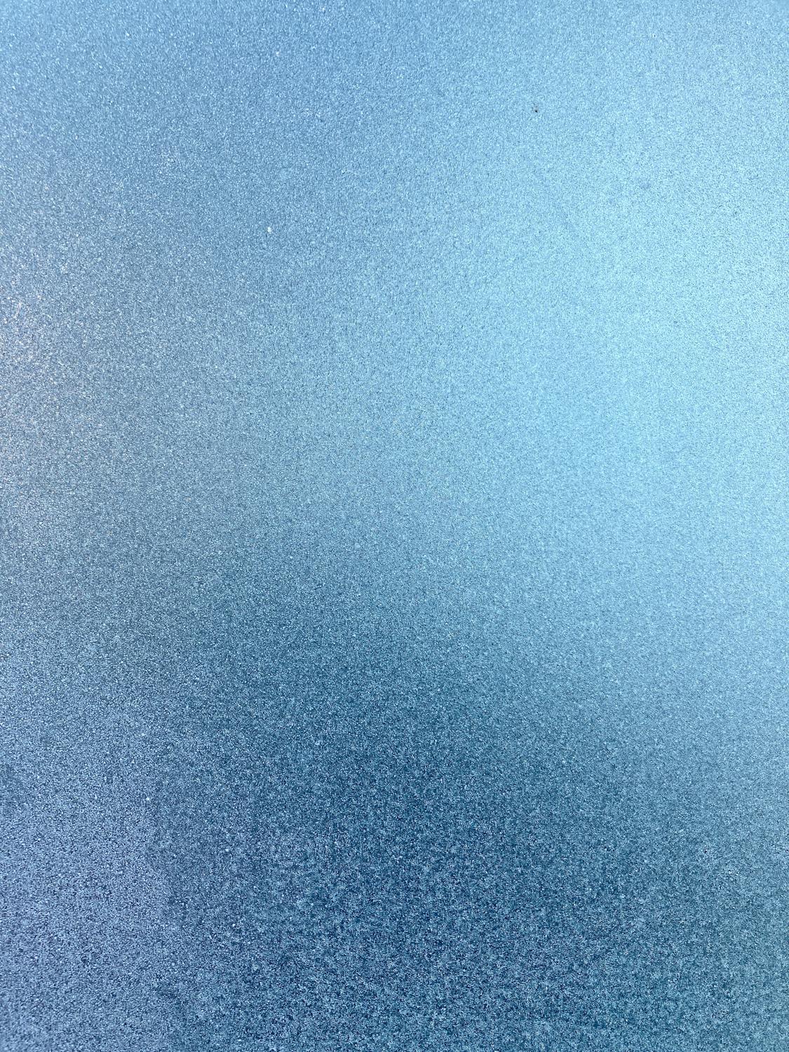 A close-up of frosted glass with soft textures and gradients — a visual metaphor for Apple's Liquid Glass design language and its translucency controversy