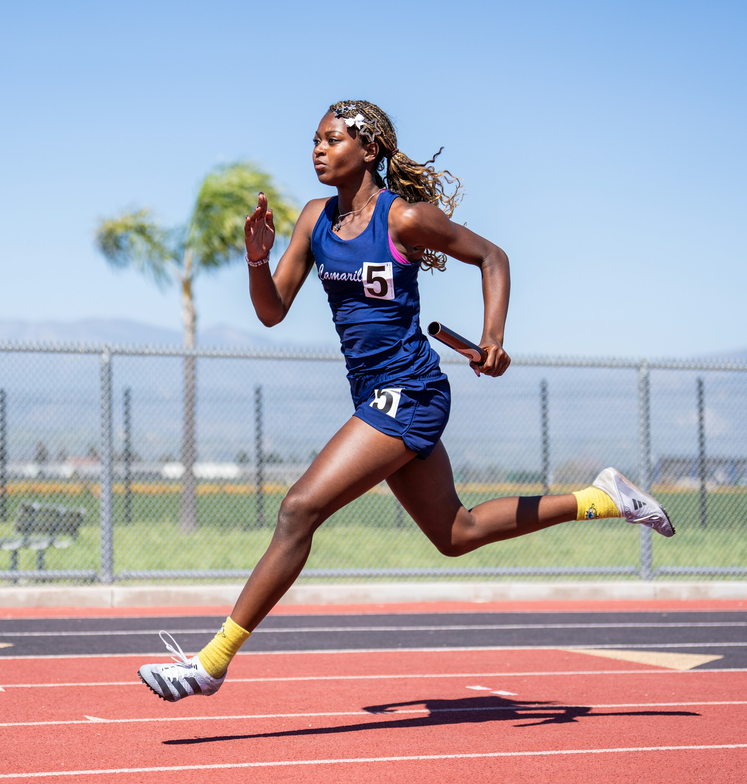 A relay runner mid-sprint on an outdoor track, baton in hand, captured at full stride — the same shape as a request that has to keep moving forward through a dropped connection, an expired token, or a second caller asking for the same thing.