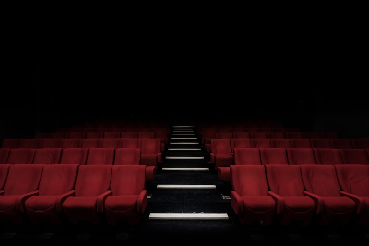 Empty red theater seats in darkness — a silent audience