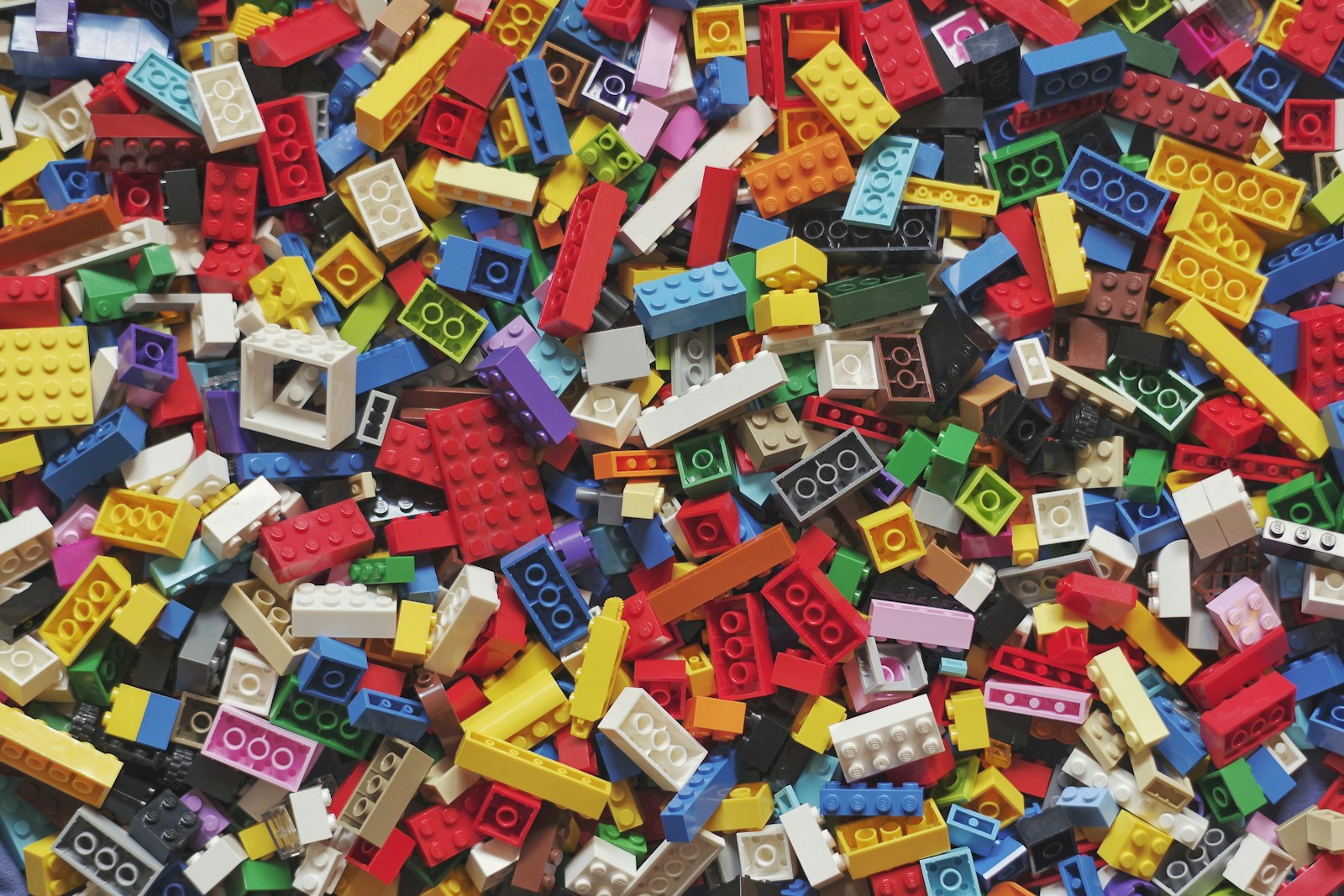 Colorful LEGO bricks — yellow, red, blue, and green — scattered on a white surface.
