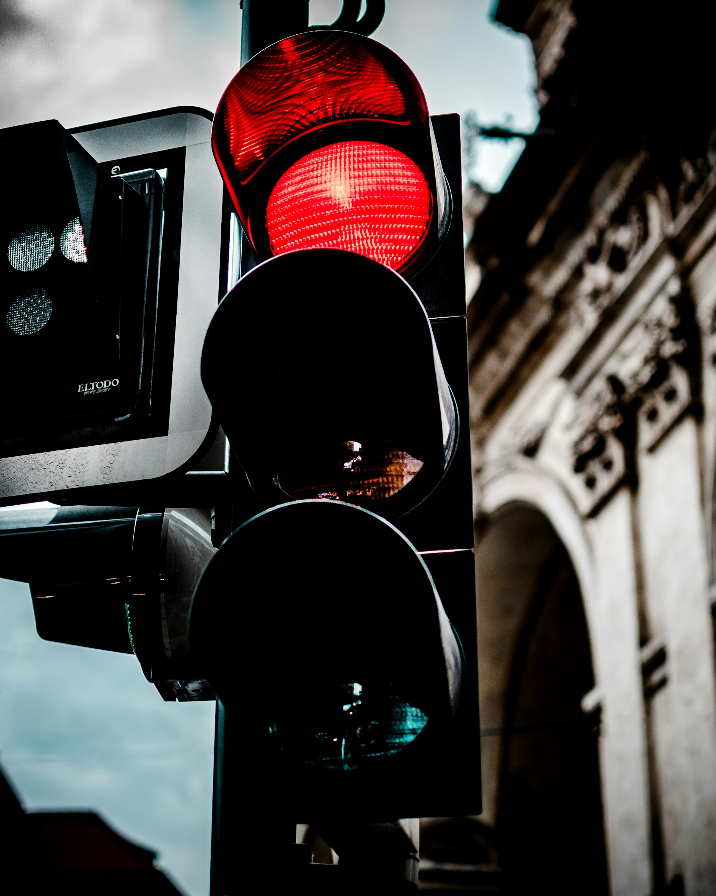A red traffic light glowing above an unlit green light on a city street — the stop-then-go cycle that gives test-driven development its name.