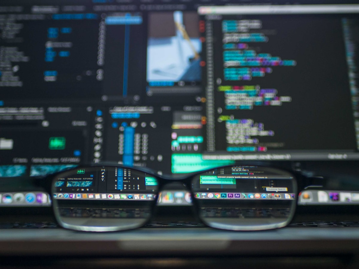 Developer screens through glasses showing code and dashboards — representing the blurry metrics behind tokenmaxxing at Big Tech companies