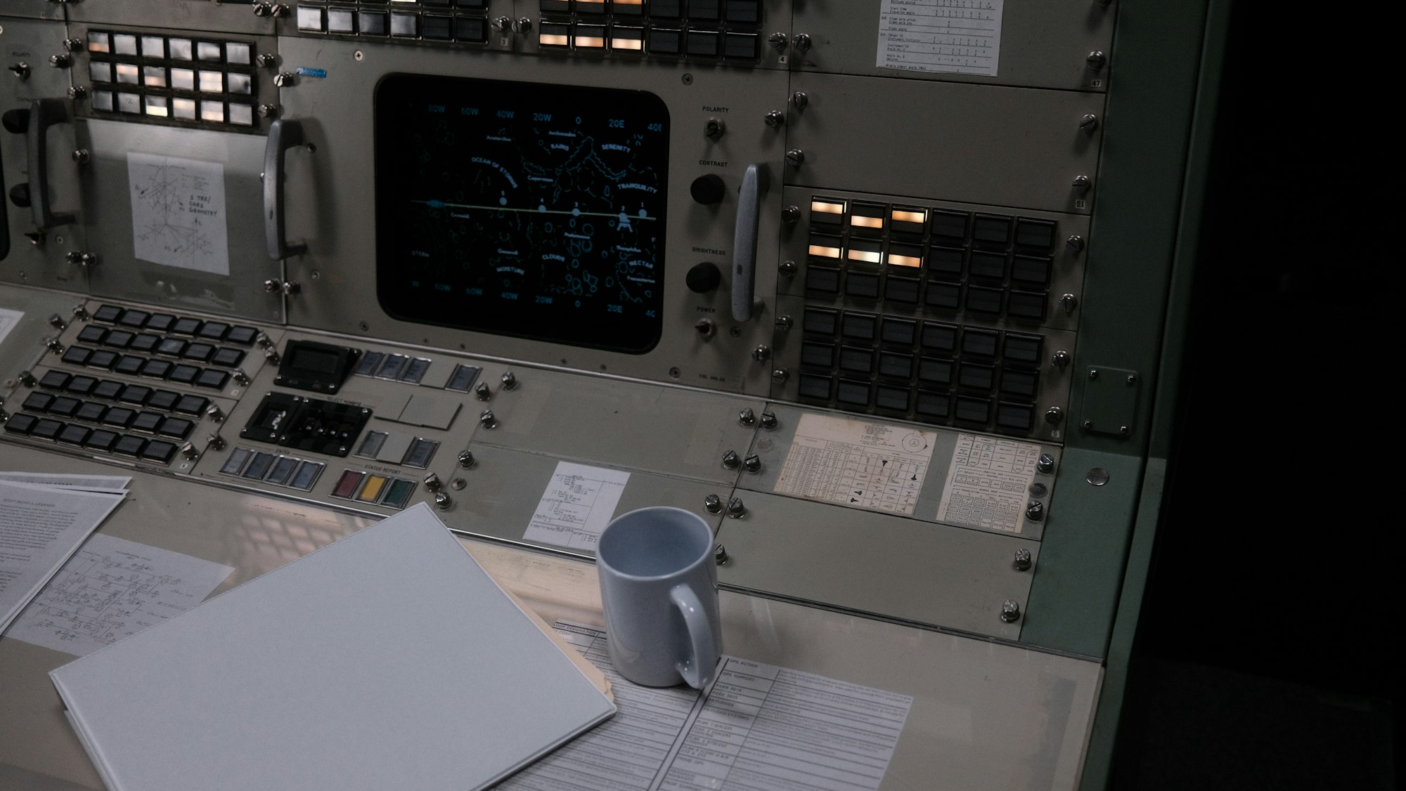 A mission control room viewed from above with rows of workstations and glowing monitors — representing the shift from code editor to agent fleet management dashboard